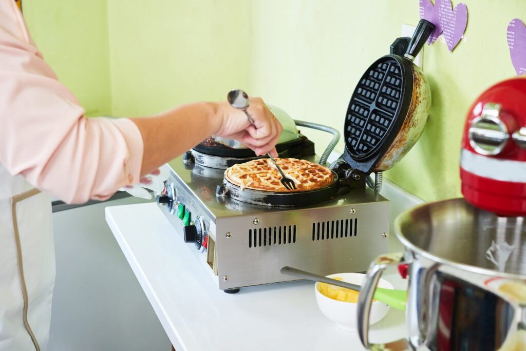 Tudo sobre chapas para lanches: qual a melhor para você? 1 woman taking fresh waffle out of waffle maker
